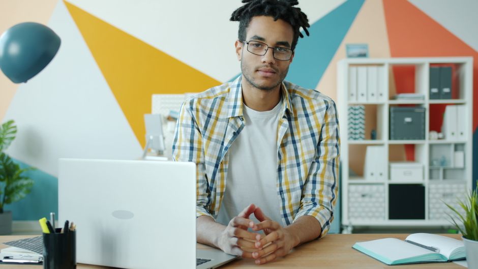 Jovem profissional trabalhando em uma mesa de escritório moderna e colorida.