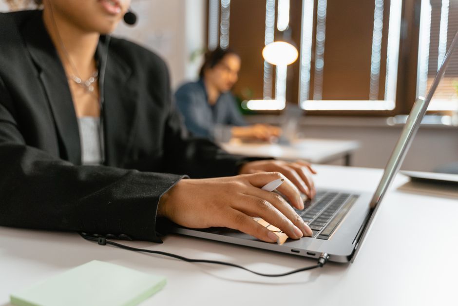 Agentes de call center trabalhando em laptops em um escritório moderno.