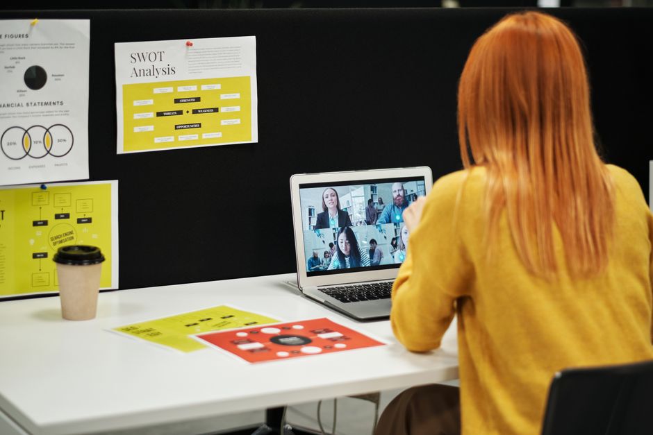 Executiva conduz reunião virtual pelo laptop em sua mesa de escritório.