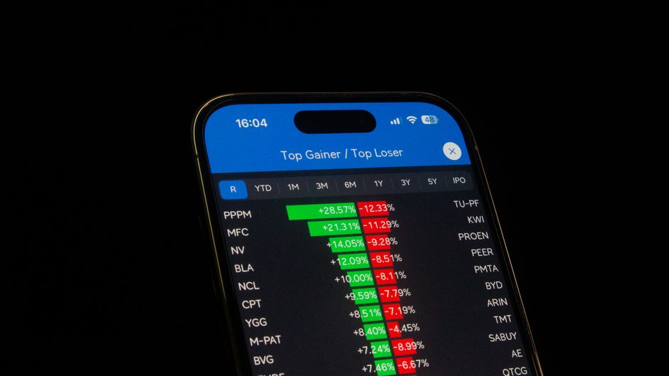 Close-up de um smartphone mostrando o desempenho de ações em um aplicativo de trading. Ideal para temas financeiros e de negócios.