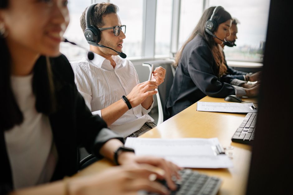 Uma equipe diversificada de agentes de call center trabalhando junta em um ambiente de escritório moderno.