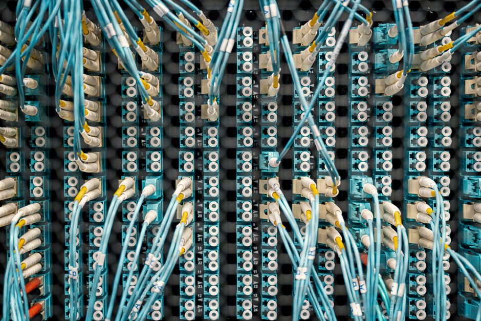 Close-up de um painel de patch de rede com cabos conectados em um data center, mostrando a gestão organizada dos cabos.