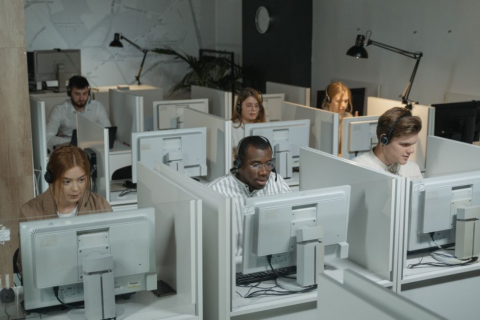 Equipe de suporte ao cliente profissional trabalhando com fones de ouvido em um ambiente de escritório moderno.