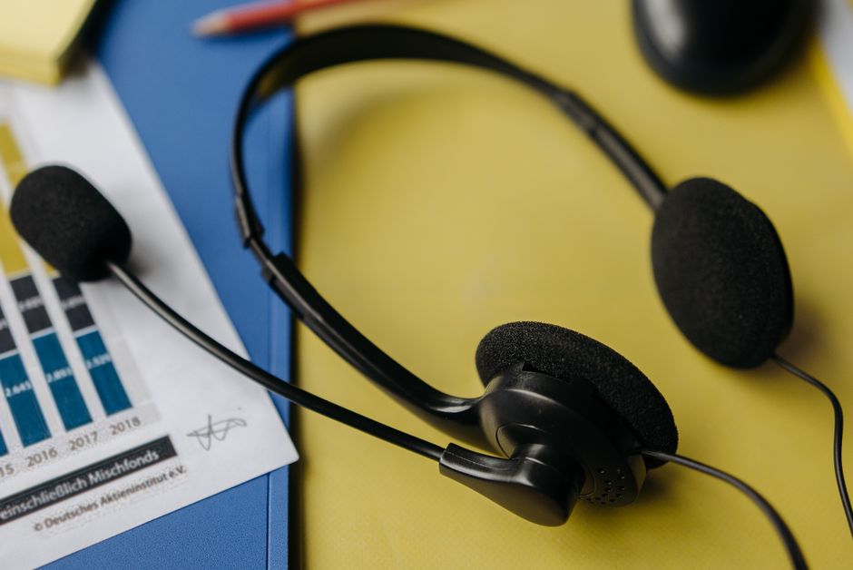 Close-up de um headset em uma mesa de trabalho com gráficos e material de escritório.